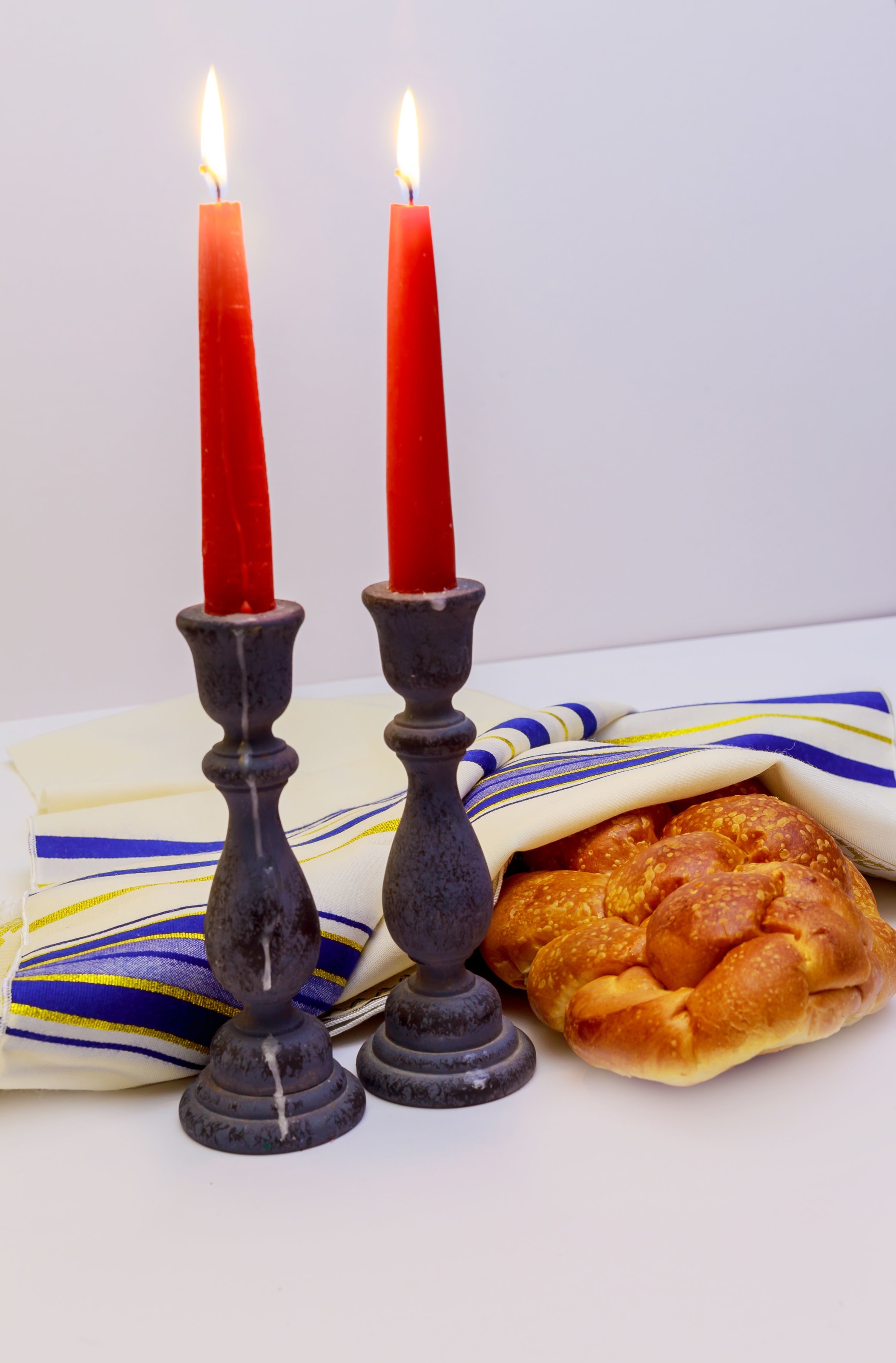 A table set for Shabbat with lighted candles, challah bread and wine